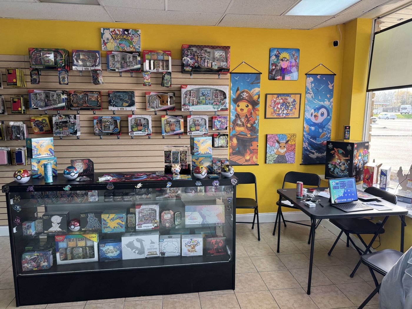 Wall of sealed Pokémon TCG product — ETBs, premium collections, and tins — with anime canvas art